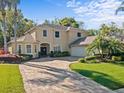 Charming two-story home featuring a brick paver driveway, lush landscaping, and a side-entry garage at 5325 Cypress Reserve Pl, Winter Park, FL 32792
