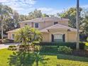 A beautifully landscaped two-story home with mature palm trees, lush shrubbery, and vibrant green lawn at 5325 Cypress Reserve Pl, Winter Park, FL 32792