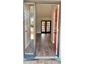 Bright entryway with hardwood floors and a red door leading to the living room with french doors at 5830 Beechmont Blvd, Orlando, FL 32808