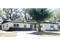 Inviting single story home featuring white siding, dark gray base, and a vibrant red front door at 5830 Beechmont Blvd, Orlando, FL 32808