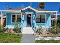 Inviting blue house featuring a quaint porch with white steps and lush garden at 723 Dougherty St, New Smyrna Beach, FL 32168