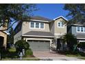 Charming two-story home featuring an attached two-car garage with brick paver driveway and mature landscaping at 7609 Brookhurst Ln, Kissimmee, FL 34747