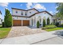 A home showcasing a brick driveway, white exterior, and grand archway entryway with a well-maintained lawn and landscaping at 8025 Topsail Pl, Winter Garden, FL 34787
