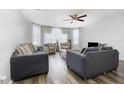 Bright living room with wood floors, plush sofas, armchairs, a ceiling fan, and large windows with sheer curtains at 8711 Rockingham Ter # A, Kissimmee, FL 34747