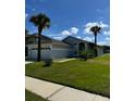 Charming single-story home featuring a two-car garage, well-manicured lawn, and palm trees at 1623 Bridgeview Cir, Orlando, FL 32824