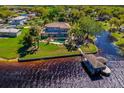 Aerial view of waterfront home featuring lush lawn, mature palms, pool and spa, and private boat dock with covered boathouse at 2112 Shady Ln, Geneva, FL 32732