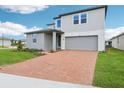 A modern two-story home with a brick driveway, a gray two-car garage, and manicured landscaping at 2933 Wild Olive Dr, St Cloud, FL 34772