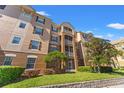 Low angle of multi-story condo building with exterior balcony, neutral colors, and manicured landscaping at 3332 Robert Trent Jones Dr # 20703, Orlando, FL 32835
