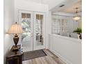 Welcoming entryway featuring double glass doors, light wood floors, and a decorative lamp and table at 3352 Park Grove Ct, Longwood, FL 32779