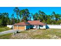 Inviting single-story home with a two-car garage, solar panels, and a fenced yard surrounded by lush trees at 11507 Lake Dr, Leesburg, FL 34788