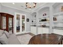Elegant office space featuring built-in bookshelves, granite countertops, and a view into the living room at 13628 Abberwick Dr, Orlando, FL 32832