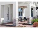 Covered front porch featuring brick columns and patio seating with manicured garden beds at 14399 Wabasso Loop, Winter Garden, FL 34787