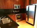 Modern kitchen with stainless steel appliances, sleek black backsplash, and wood cabinets at 155 S Court Ave # 1613, Orlando, FL 32801