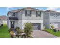 Charming two-story home with a gray garage and brick-paved driveway at 17398 Saw Palmetto Ave, Clermont, FL 34714