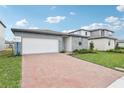 Stylish single-Gathering home with a brick driveway, modern gray siding, and a well-maintained lawn at 2929 Wild Olive Dr, St Cloud, FL 34772