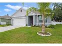 Home featuring a palm tree in the front yard, complemented by lush green grass and tasteful landscaping, creating a tropical feel at 1150 August Sky Dr, Deltona, FL 32738