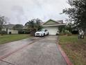 Front exterior of home featuring a two-car garage, long driveway, and manicured lawn at 123 Breezy Oaks Ct, Davenport, FL 33896