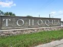 Community signage with stone base and green landscaping on a sunny day at 1696 Tohoqua Blvd, Kissimmee, FL 34744