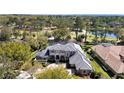 Aerial view of a large luxury home with a tile roof surrounded by trees, golf course and a pond at 1707 Stetson Ct, Longwood, FL 32779