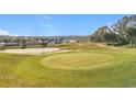 Scenic golf course view featuring a pristine green with sand traps and a lake in the distance at 3635 Kingswood Ct, Clermont, FL 34711