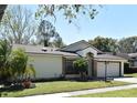 Lovely single Gathering home featuring a lush green lawn, attached garage, and mature trees against a blue sky at 691 Monroe Harbor Pl, Sanford, FL 32773