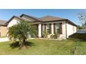 Well-maintained home exterior with a palm tree, lush lawn, and partial lake view at 8878 Conway Rd, Polk City, FL 33868