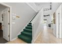 Bright entryway with green carpeted stairs, white railings, and tile flooring at 1207 Winding Cypress Ct, Kissimmee, FL 34746