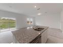 Kitchen island featuring granite countertops, stainless steel sink, and ample counter space at 1409 Dalkeith Cv, Sanford, FL 32771