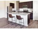 Modern kitchen with stainless steel appliances, a granite countertop island, and dark wood cabinets at 1415 Dalkeith Cv, Sanford, FL 32771