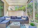 Relaxing screened porch with comfortable blue seating, glass table, and view of the beautiful trees in the backyard at 4952 Matteo Trl, Orlando, FL 32839