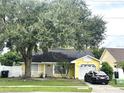 Lovely yellow home with an attached garage, enhanced by mature tree and front lawn landscaping at 1018 Martin Blvd, Orlando, FL 32825