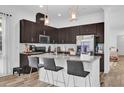 Modern kitchen featuring dark cabinets, a gray countertop island with seating, and stainless steel appliances at 10257 Henbury St, Orlando, FL 32832