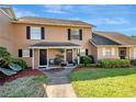 Charming townhouse exterior with lush landscaping, black shutters, and a quaint front yard seating area at 1174 Villa Ln # 115, Apopka, FL 32712