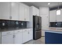 Close-up of a kitchen featuring white cabinetry, a stainless steel refrigerator, and a dark backsplash at 11810 Imaginary Way, Orlando, FL 32832
