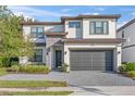 Two story home featuring a paved driveway, two car garage, stone accents, and manicured landscaping at 1205 Butterfly Orchid Rd, Davenport, FL 33837