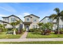 Charming two-story home featuring a manicured lawn, walkway lighting, and lush tropical landscaping at 17087 Wynford Ln, Winter Garden, FL 34787