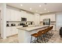 Bright kitchen boasts stainless steel appliances, white cabinetry, island with breakfast bar and tile floors at 2145 Fleming Mist Pl, Kissimmee, FL 34747