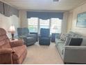 Cozy living room showcasing comfortable seating, neutral carpet, and large windows dressed with decorative valances at 223 Pinewood Dr, Eustis, FL 32726