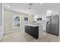 Modern kitchen features white cabinetry, stainless steel appliances, and a dark island with quartz countertop and pendant lighting at 2418 Whitehall Cir, Winter Park, FL 32792