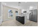 Modern kitchen features white cabinets, stainless steel appliances, and an island with a black base and quartz countertop at 2418 Whitehall Cir, Winter Park, FL 32792