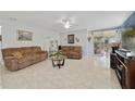 Bright living room with tile flooring, two brown sofas, ceiling fan, and sliding glass doors to the outdoors at 3823 Ryegrass St, Clermont, FL 34714