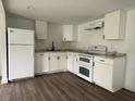Bright kitchen featuring white cabinetry, modern appliances, dark hardware, and stylish wood-look flooring at 3931 Avenue R Nw, Winter Haven, FL 33881