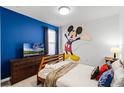 Bright bedroom with twin bed, blue accent wall and large Mickey Mouse decal at 5260 Oakbourne Ave, Davenport, FL 33837