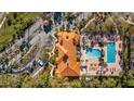 An aerial view of a complex featuring pools, palm trees, parking, landscaping and a building with terra cotta roof at 5483 Vineland Rd # 10103, Orlando, FL 32811