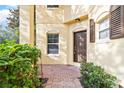 Inviting front entrance with beautiful landscaping and brick walkway leading to a brown front door at 6881 Piazza St, Orlando, FL 32819