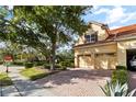 Paver driveway leads to a three car garage, with well-maintained landscaping and mature shade trees at 6881 Piazza St, Orlando, FL 32819