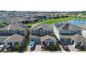 Aerial view of a two-story home with a manicured lawn in a lakeside community with solar panels on several houses at 10732 Petrillo Way, Winter Garden, FL 34787