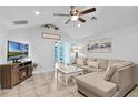 Bright living room features tile flooring, ceiling fan, vaulted ceiling, and sliding door to the backyard at 19624 E Umatilla Blvd, Umatilla, FL 32784