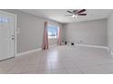 Bright living room featuring tile flooring, a ceiling fan, and a window with pink curtains at 2102 Nedra Ave, Deltona, FL 32725