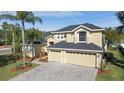 Aerial view of a two-story home boasting a paver driveway, three-car garage, and manicured lawn at 2523 Water Valley Dr, St Cloud, FL 34771